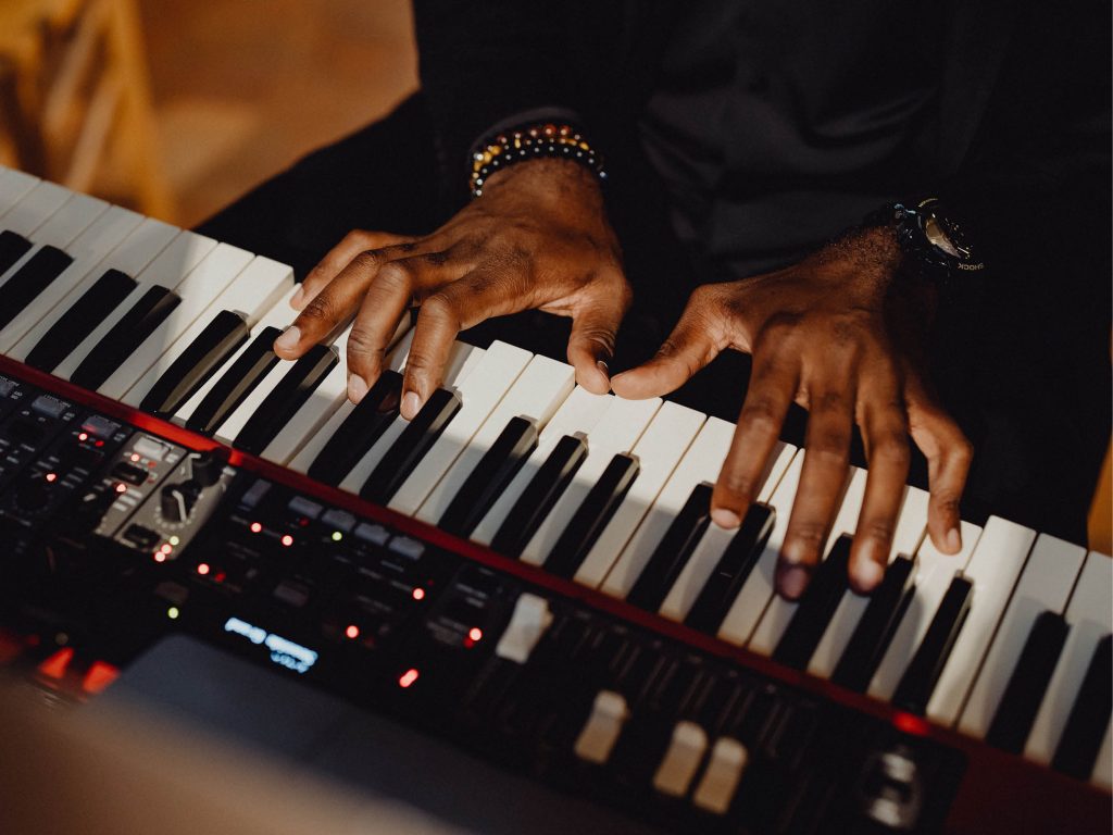 Närbild över ett piano och två händer som spelar över det.