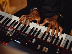 Närbild över ett piano och två händer som spelar över det.