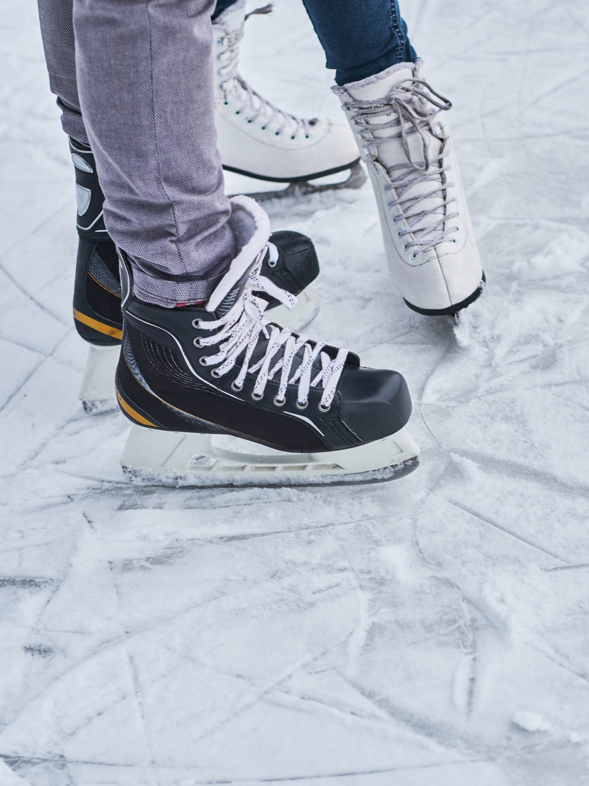 Närbild på två personers fötter insnurrade i skridsskor, vintertid över isen i Stockholm.