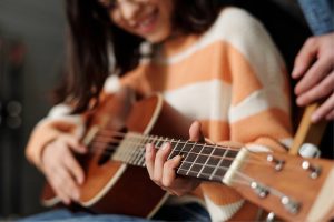 En yngre kvinna under en gitarrlektion på Midsommargården StudioUng i Stockholm.