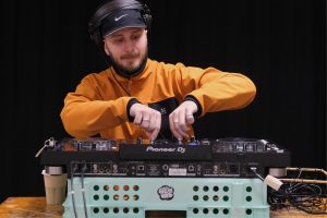 En yngre man vid ett DJ-bord som lär ut hur man DJ:ar under en kurs på Midsommargården StudioUng i Stockholm.